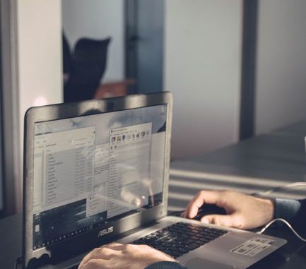 A person typing on a laptop inside an office, emphasizing technology and productivity.