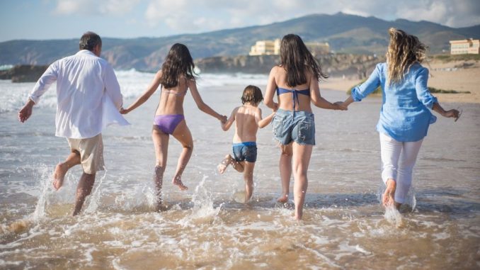 A family having fun running into the ocean on a sunny beach day in Portugal. Joyful and carefree moments.