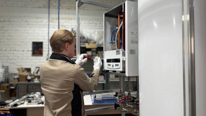 Technician inspects and repairs a heating system in an industrial workshop setting.