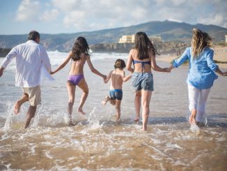 A family having fun running into the ocean on a sunny beach day in Portugal. Joyful and carefree moments.