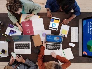 A diverse team collaborating on digital marketing strategies at a desk, using laptops and tablets.