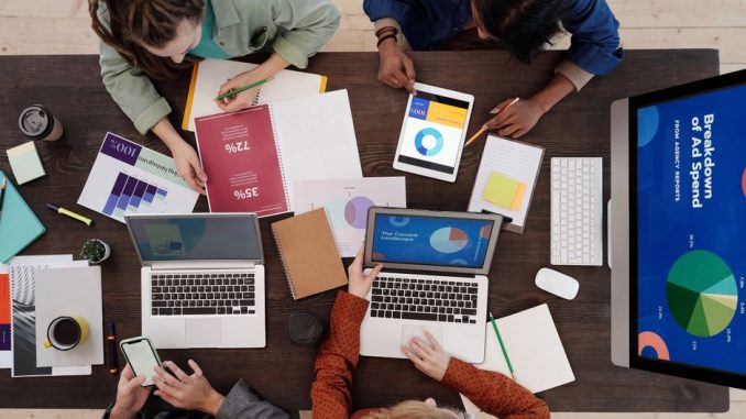 A diverse team collaborating on digital marketing strategies at a desk, using laptops and tablets.