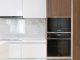 Modern interior of white and wooden kitchen with cabinets cupboards and built in appliances in contemporary flat